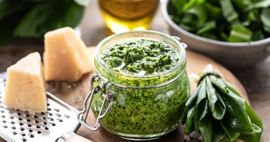 Bärlauchpesto mit Olivenöl und Parmesankäse im Glas auf einem Holztisch