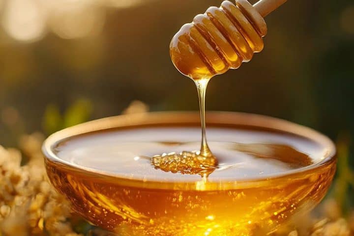 Goldglänzender Honig läuft von einem Honiglöffel