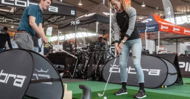 Eine Golferin testet Equipment auf einem Indoor-Grün in der Messehalle