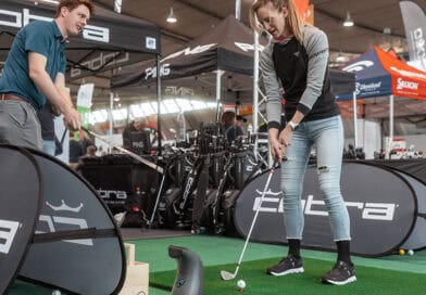 Eine Golferin testet Equipment auf einem Indoor-Grün in der Messehalle