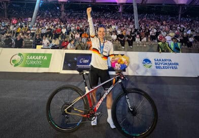 Marion Fromberger strahlt nach ihrem erfolgreichen Rennen in Sakarya und hebt die rechte Faust zum Sieg. In der linken Hand hält sie einen Blumenstrauß und ihr Corratec MTB.
