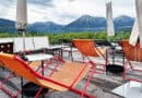 Orangefarbene Liegestühle auf der Dachterrasse des Hotel Bussi Baby vor der Tegernseer Bergkulisse.