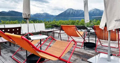 Orangefarbene Liegestühle auf der Dachterrasse des Hotel Bussi Baby vor der Tegernseer Bergkulisse.