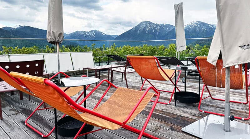 Orangefarbene Liegestühle auf der Dachterrasse des Hotel Bussi Baby vor der Tegernseer Bergkulisse.