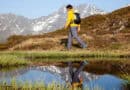Bergwanderführer Georg Pawlata unterwegs in einer alpinen Landschaft. Im Vordergrund ein See, in dem er sich spiegelt.
