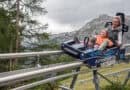Eine Erwachsene und ein Kind fahren gemeinsam mit dem ELFERCOASTER auf einer Schienenrodelbahn vor der Bergkulisse des Stubaitals.