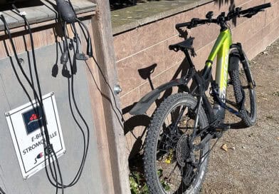 corratec E-Power X-Vert Pro Team an einer öffentlichen E-Bike-Ladestation.