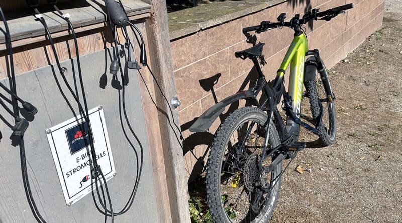 corratec E-Power X-Vert Pro Team an einer öffentlichen E-Bike-Ladestation.