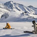 Zwei Skifahrer auf frisch präparierter Piste am Stubaier Gletscher vor verschneiter Bergkulisse.