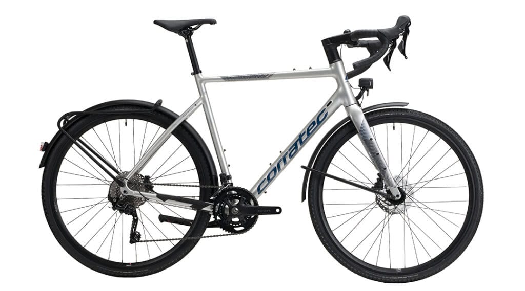 Silbernes corratec ALLROAD A EQ Gravelbike mit Schutzblechen, Gepäckträger, Lichtanlage und Rennlenker in Seitenansicht.