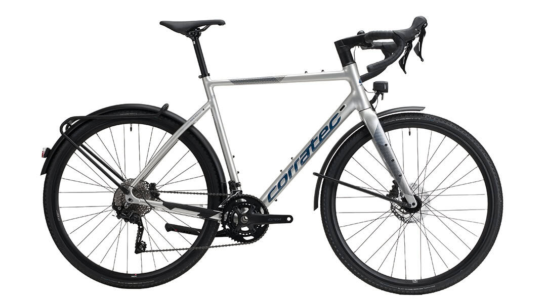 Silbernes corratec ALLROAD A EQ Gravelbike mit Schutzblechen, Gepäckträger, Lichtanlage und Rennlenker in Seitenansicht.