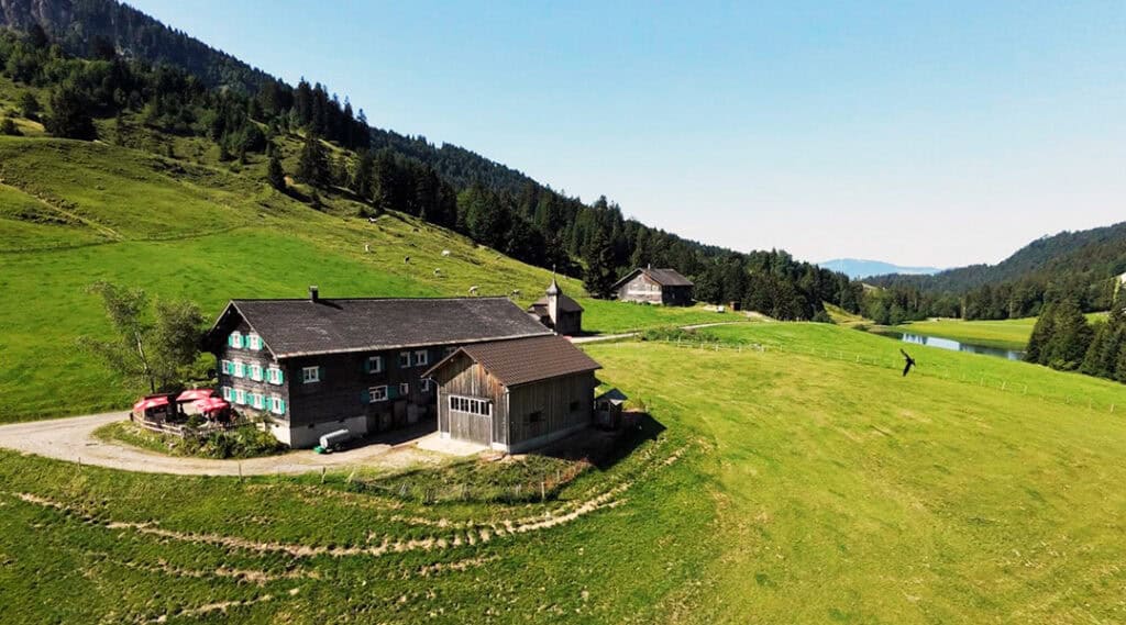 Alpe Höfle im grünen Lecknertal mit Alpengasthof, Bergwiesen, Wald und See.
