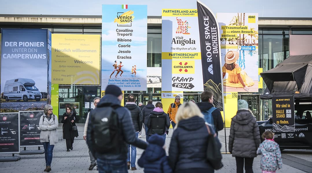 Besucherinnen und Besucher vor dem Eingang der CMT auf dem Messegelände Stuttgart mit großformatiger Tourismus- und Campingwerbung.