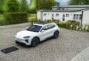 Weißer Porsche Cayenne Electric steht über einer Bodenplatte für kabelloses Laden auf einem privaten Stellplatz.