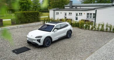 Weißer Porsche Cayenne Electric steht über einer Bodenplatte für kabelloses Laden auf einem privaten Stellplatz.