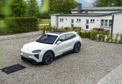 Weißer Porsche Cayenne Electric steht über einer Bodenplatte für kabelloses Laden auf einem privaten Stellplatz.