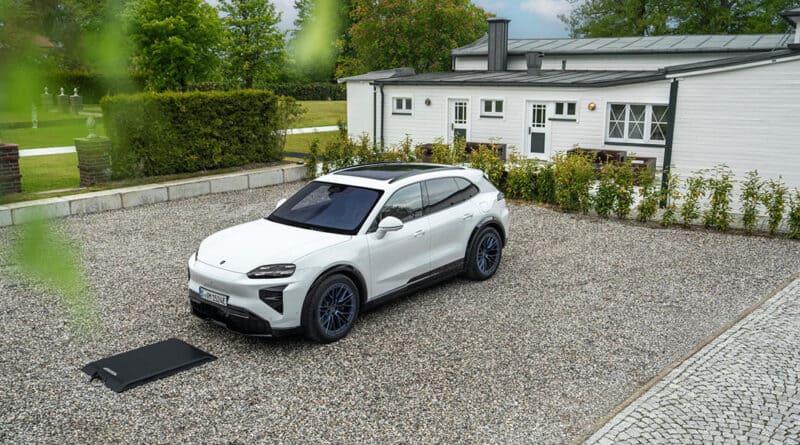 Weißer Porsche Cayenne Electric steht über einer Bodenplatte für kabelloses Laden auf einem privaten Stellplatz.